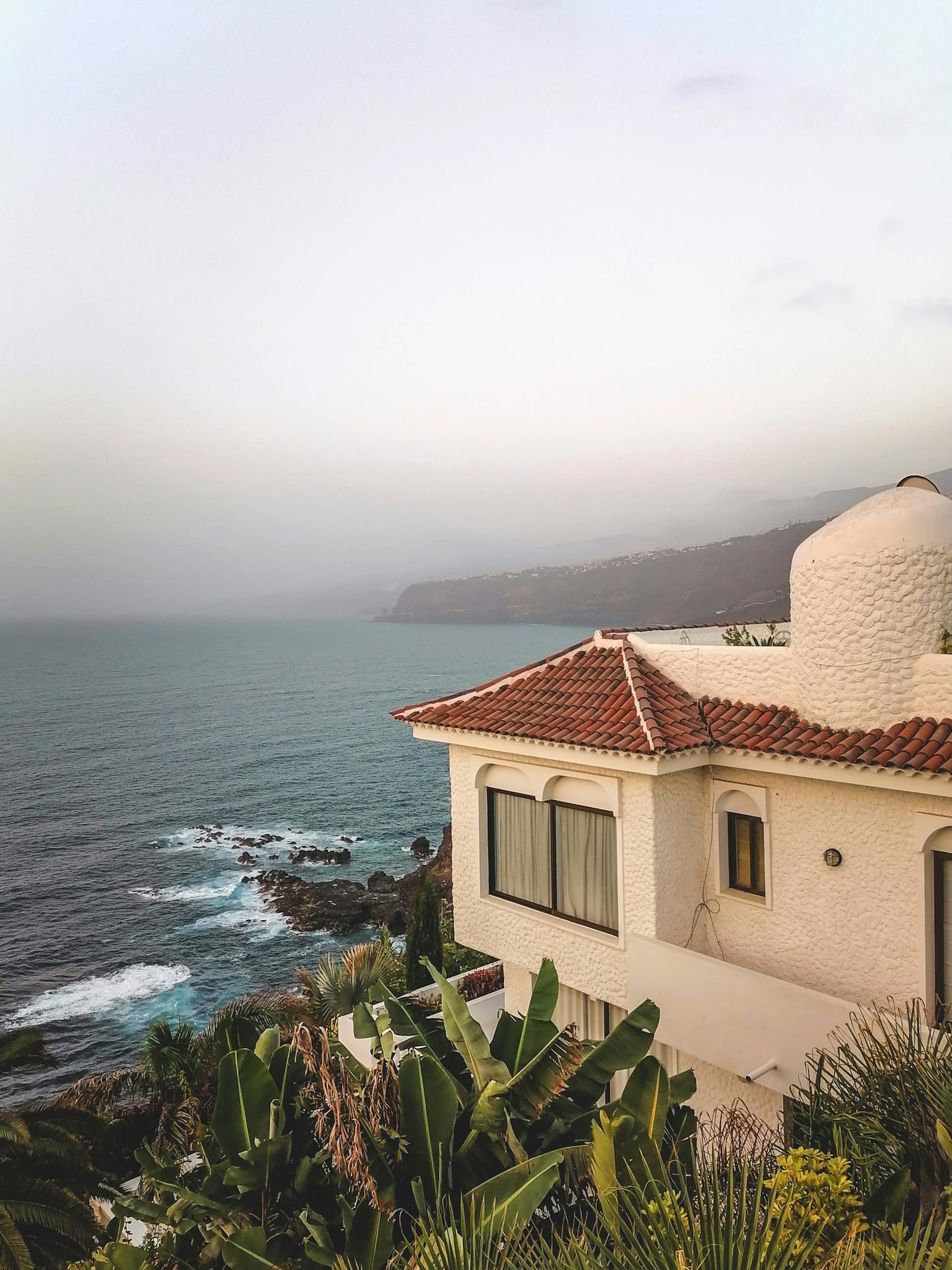 Beautiful coastal villa overlooking the sea in CN, Spain with lush greenery.