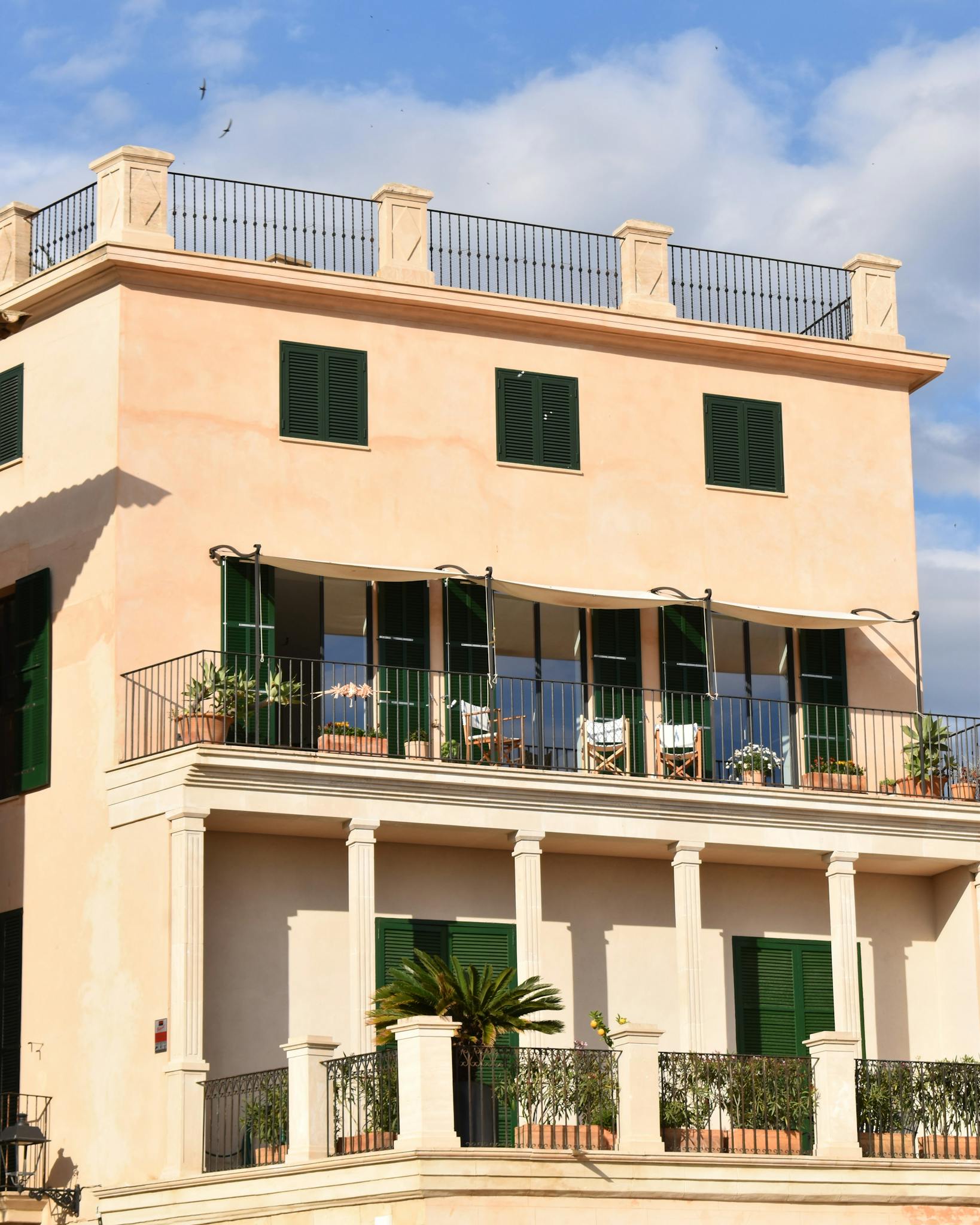 Elegant Mediterranean villa exterior with spacious balcony and potted plants.