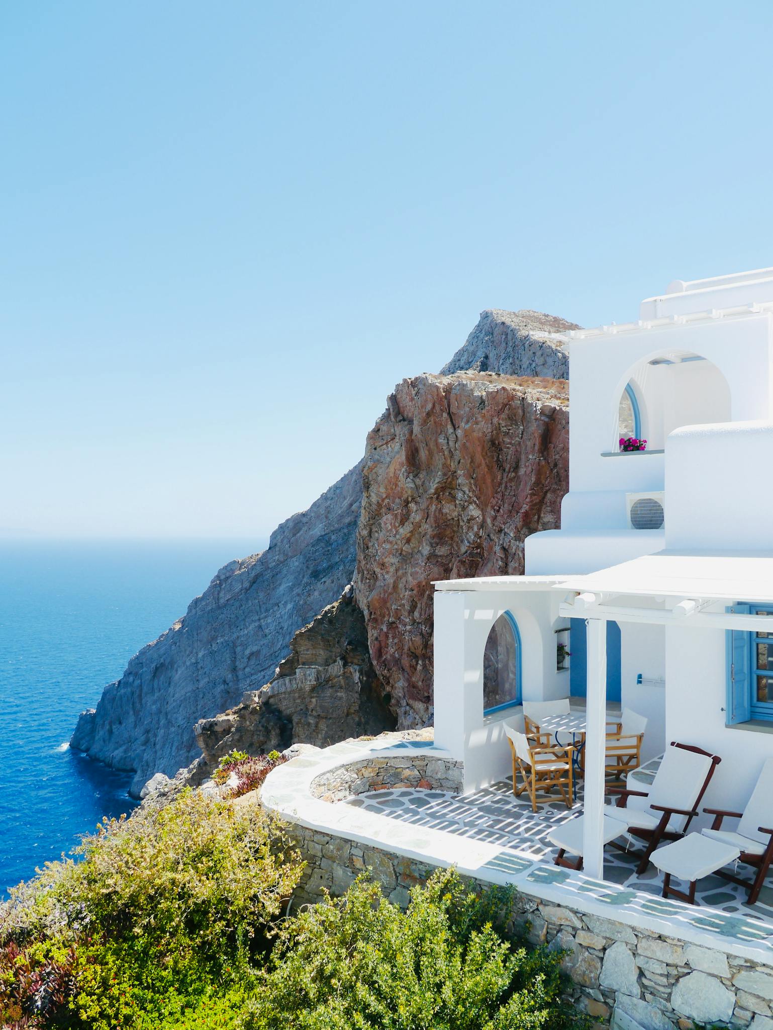 Elegant white villa on Santorini cliffside with stunning Aegean Sea view. Captures Greek island charm.